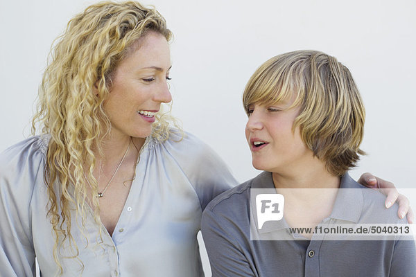 Mittlere erwachsene Frau und ihr Sohn schauen sich an und lächeln.