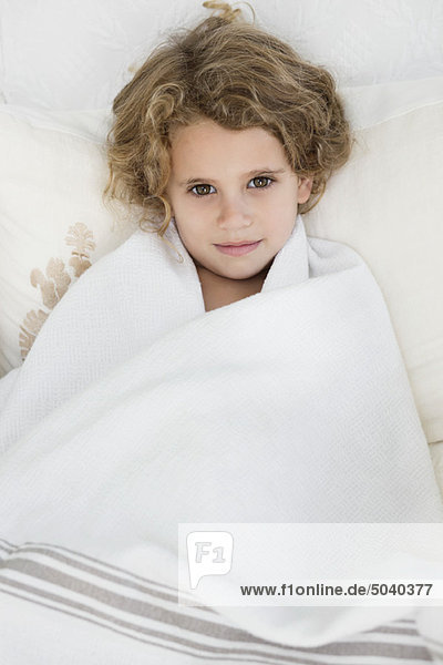 Portrait of a cute little girl wrapped in a white towel