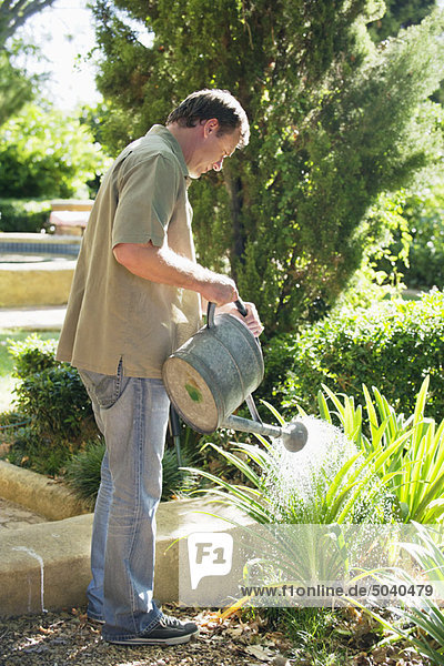 Seitenprofil eines reifen Mannes beim Gießen von Pflanzen in einem Garten