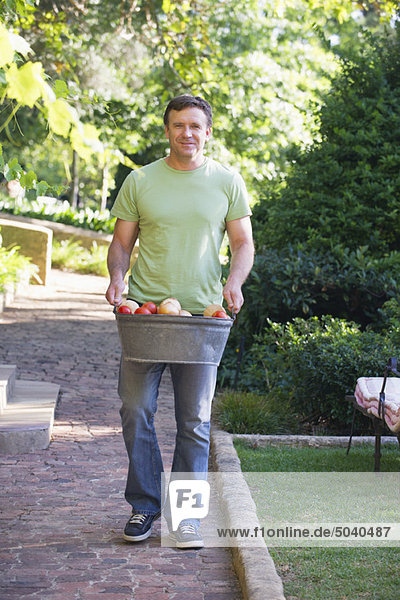 Reifer Mann mit Obstkorb im Garten