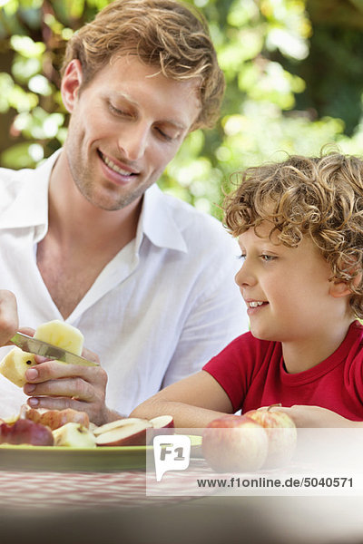Father peeling apple with son