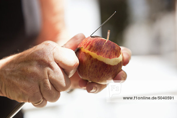 Nahaufnahme der Männerhand beim Schälen eines Apfels