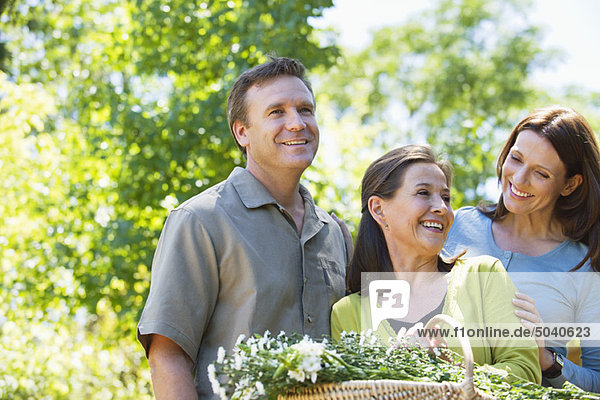 Woman standing with his son and daughter in law while holding basket of flowers