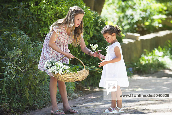 Mädchen schenkt ihrer kleinen Schwester eine Blume.
