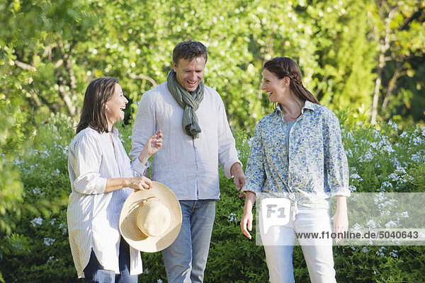 Happy mature couple standing with their mother in a garden