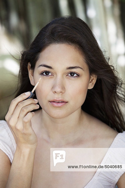 Beautiful young woman applying make-up