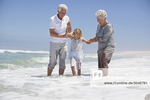 Enkelin genießt mit Großeltern am Strand