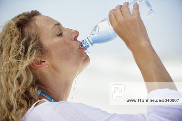 Seitenprofil einer schönen Frau beim Trinken von gereinigtem Wasser