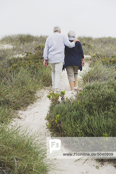 Rückansicht eines Seniorenpaares beim Spaziergang am Strand