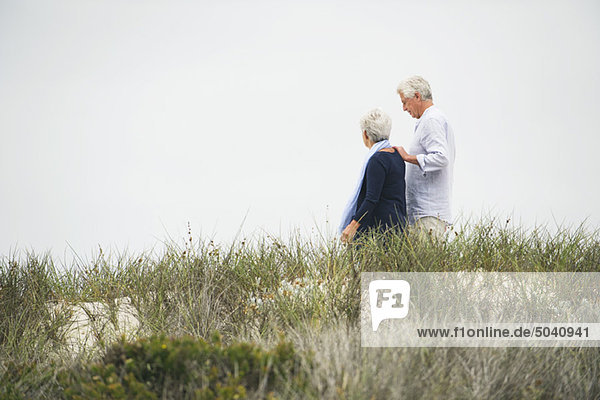 Seitenprofil eines älteren Paares  das am Strand spazieren geht