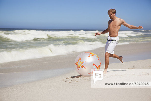 Man kicking ball on the beach
