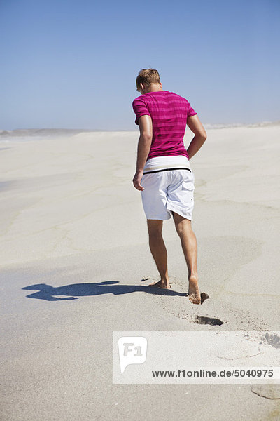Rear view of a man walking on sand