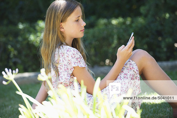 Süßes kleines Mädchen mit einem Handy im Freien