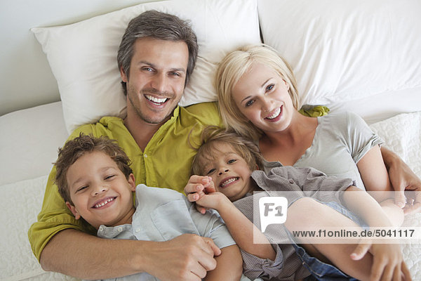 Couple with their children relaxing in bed
