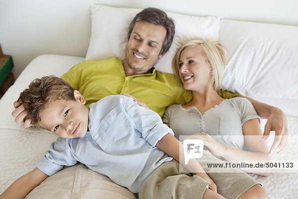 Eltern mit ihrem Sohn entspannt im Bett