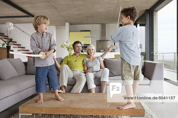 Boys playing with their parents sitting on a couch