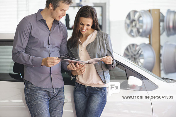 Couple looking at car catalog in showroom