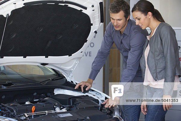 Couple looking at car engine in showroom