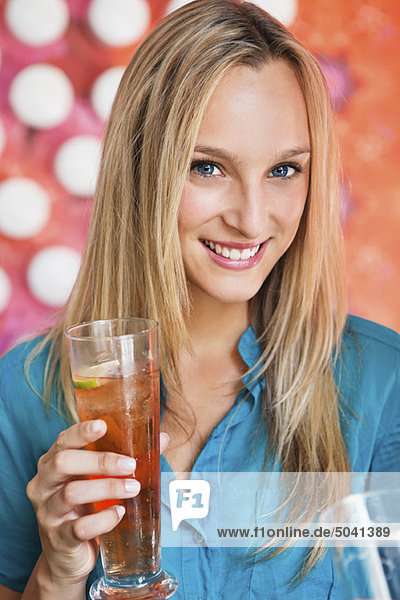 Porträt einer schönen Frau bei Eistee in einer Bar und lächelndem Lächeln