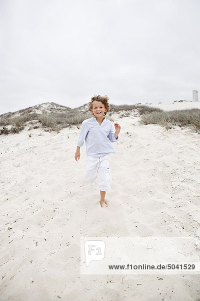 Cute boy running on sand at beach
