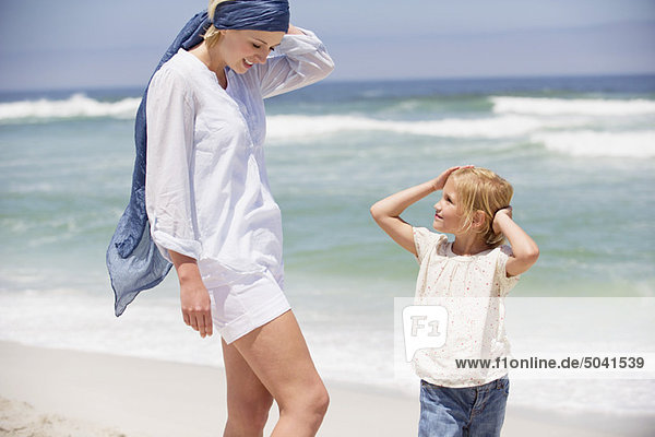 Frau mit ihrer Tochter am Strand stehend