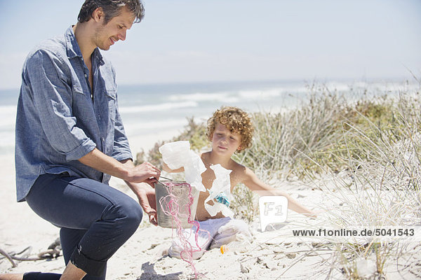 Mittlerer Erwachsener Mann und sein Sohn beim Putzen des Strandes
