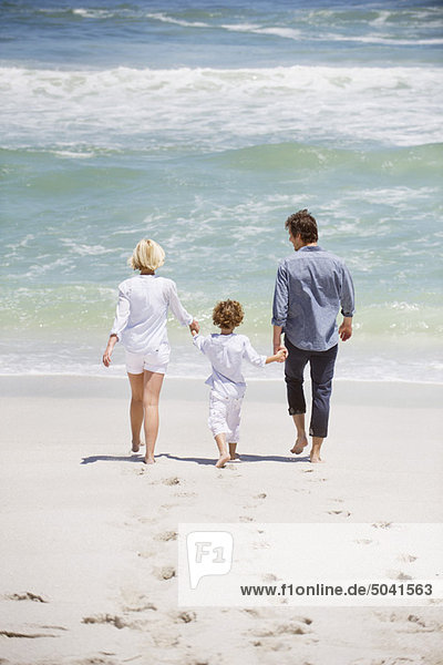 Paar mit ihrem Sohn  der am Strand spazieren geht.