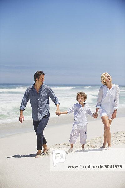 Boy walking with his parents on the beach