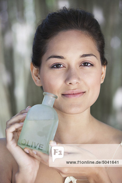 Porträt einer schönen jungen Frau mit einer Flasche Olivenöl