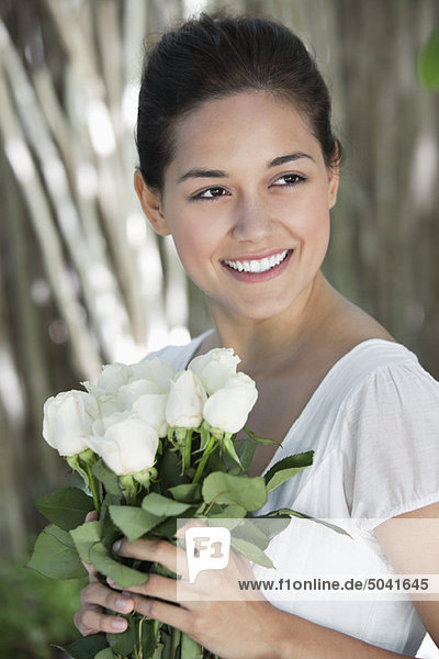Junge Frau mit einem Strauß weißer Blumen und einem Lächeln.