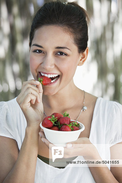 Porträt einer jungen Frau beim Erdbeeressen