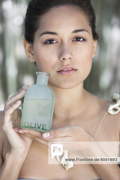 Porträt einer schönen jungen Frau mit einer Flasche Olivenöl
