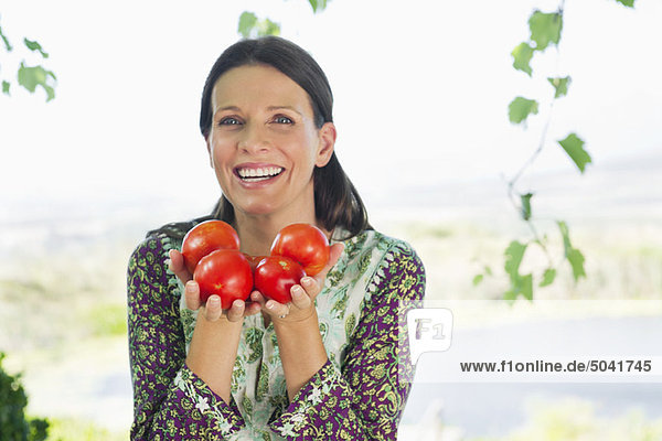Porträt einer lächelnden reifen Frau mit Tomaten