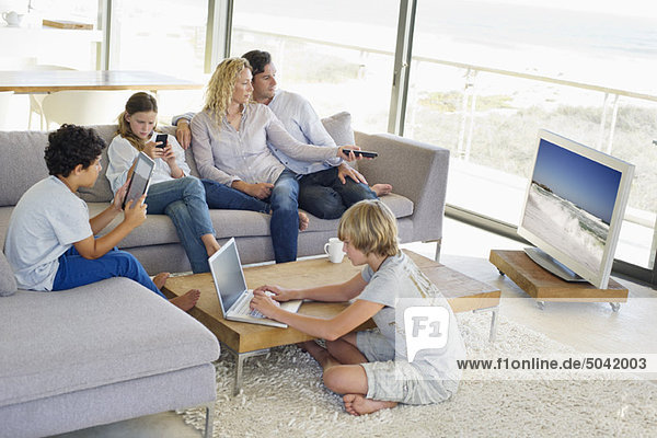 Paare  die fernsehen  während ihre Kinder in verschiedenen Aktivitäten beschäftigt sind