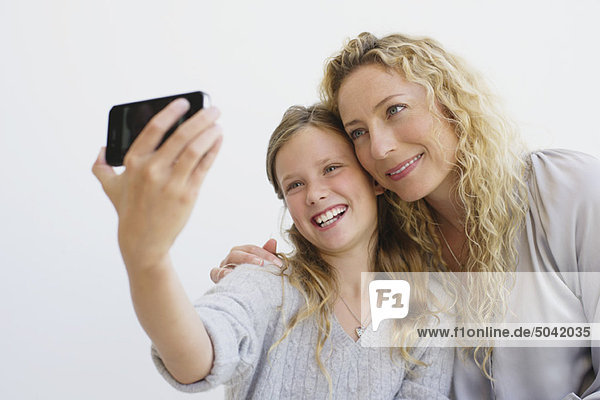 Mädchen mit ihrer Mutter beim Fotografieren mit dem Handy