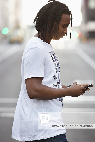Side profile of a man text messaging on a mobile phone