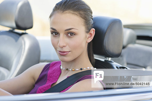 Portrait of a beautiful young woman driving a convertible car