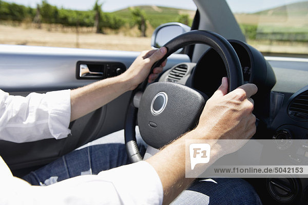 Mid adult man's hand holding a steering wheel of convertible car