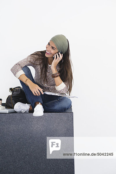 Schöne Frau spricht über Handy vor weißem Hintergrund