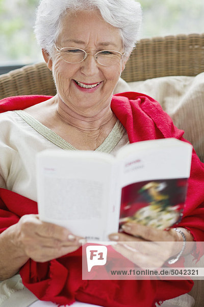Seniorin liest eine Zeitschrift und lächelt