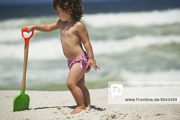 Girl playing with a sand shovel on the beach