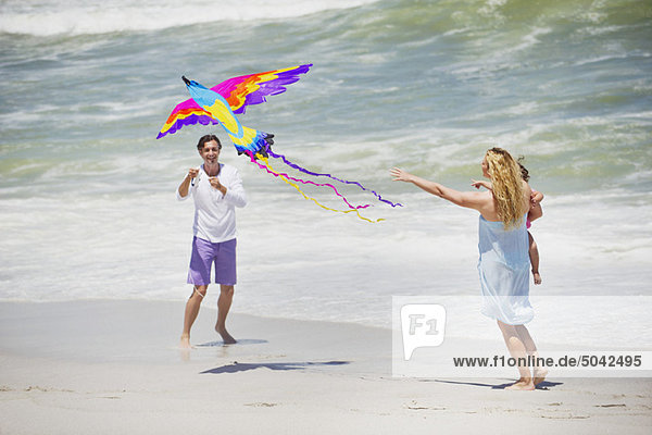 Mutter mit Kind beim Drachenfliegen am Strand