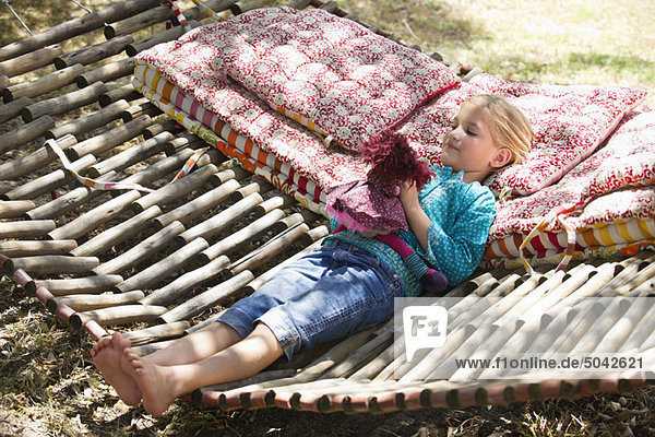 Little girl playing with toy while lying in hammock