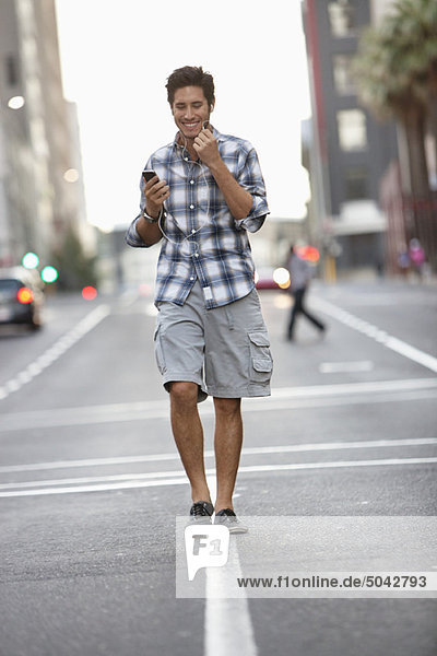 Ein Mann  der auf dem Handy spricht  während er auf der Straße unterwegs ist.