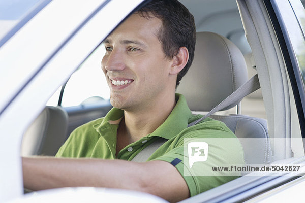 Lächelnder erwachsener Mann beim Autofahren