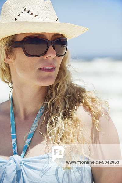 Mittlere erwachsene Frau mit Sonnenbrille und Sonnenhut