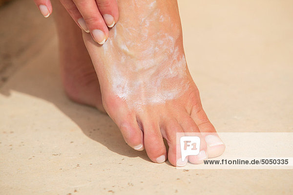 Woman moisturizing foot