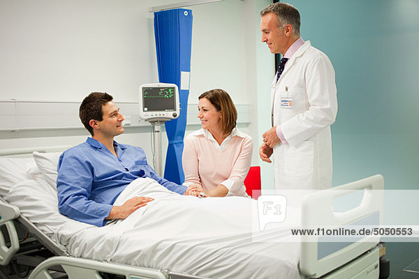 Wife visiting husband in hospital  talking to doctor