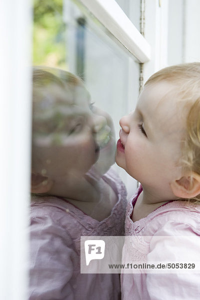 Kleinkind Mädchen schaut durchs Fenster