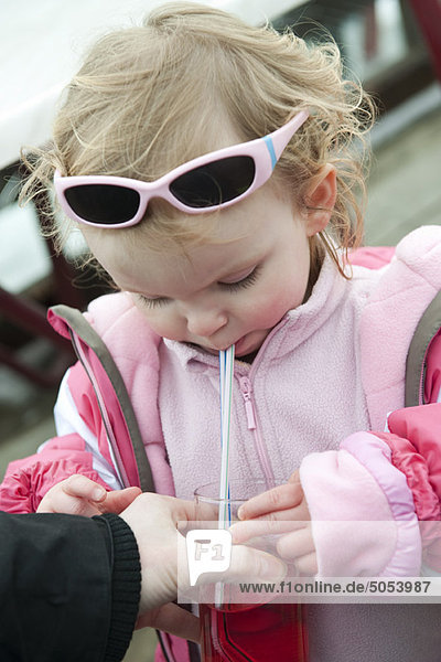 Toddler girl drinking juice with straw
